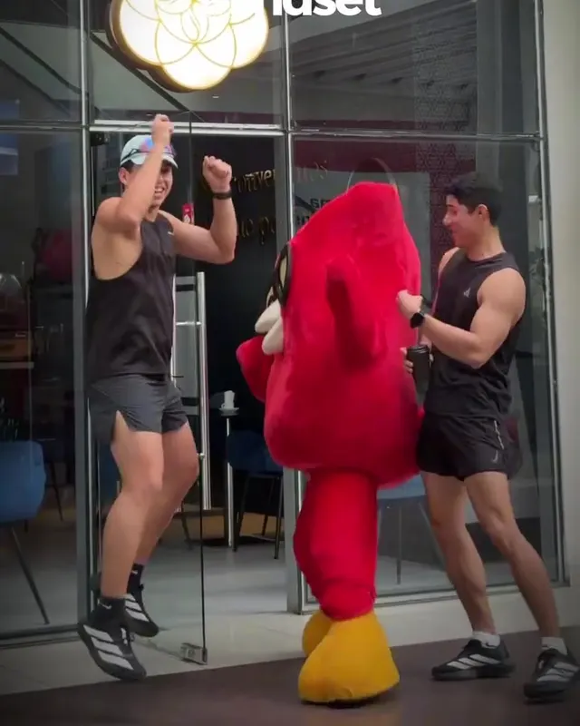 La mascota búho de Mindset bailando con un corredor frente al café